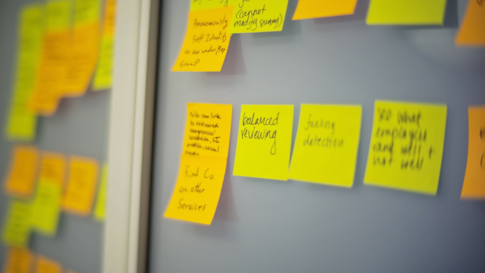 Selective focus photography of yellow and orange post it notes on wall